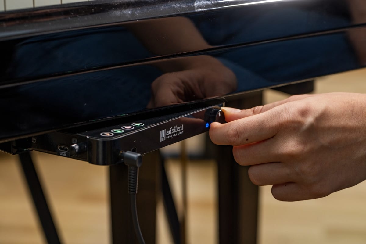 Boîtier de commande adsilent monté sous le piano, avec sortie casque accessible